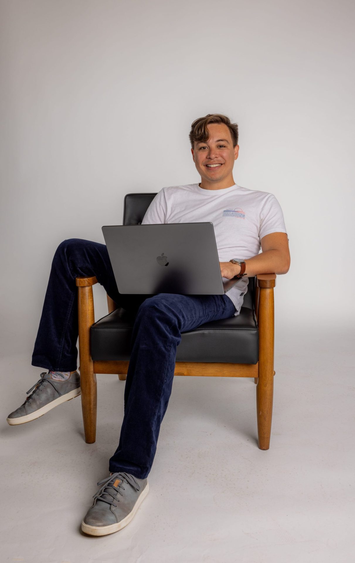 Digital Reach, Smiling man working on laptop in armchair.