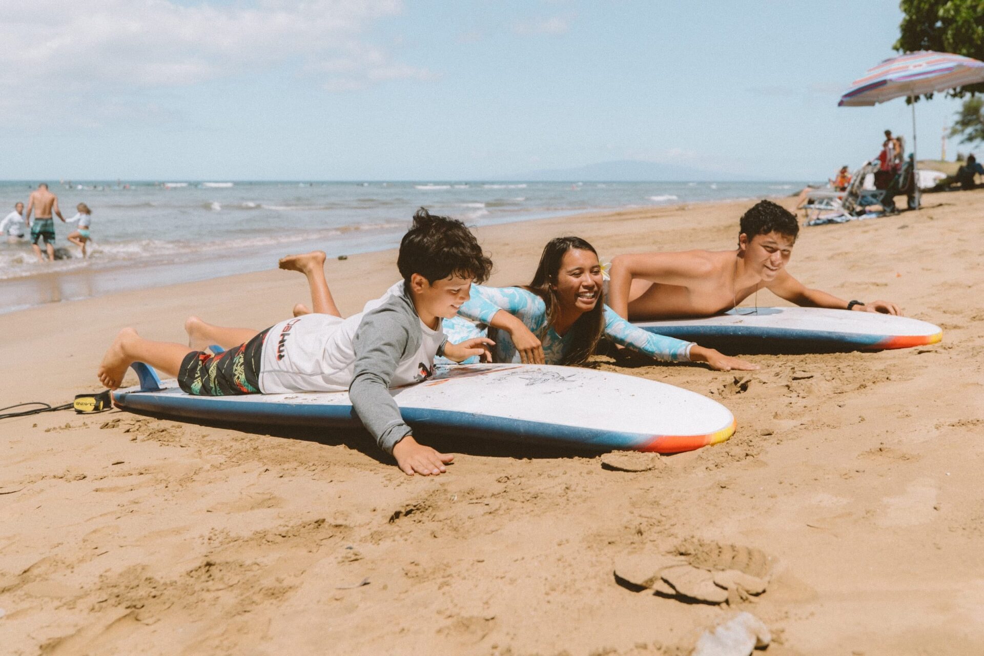 Kids and instructor lying on surfboards at the beach, ready for surfing lessons
