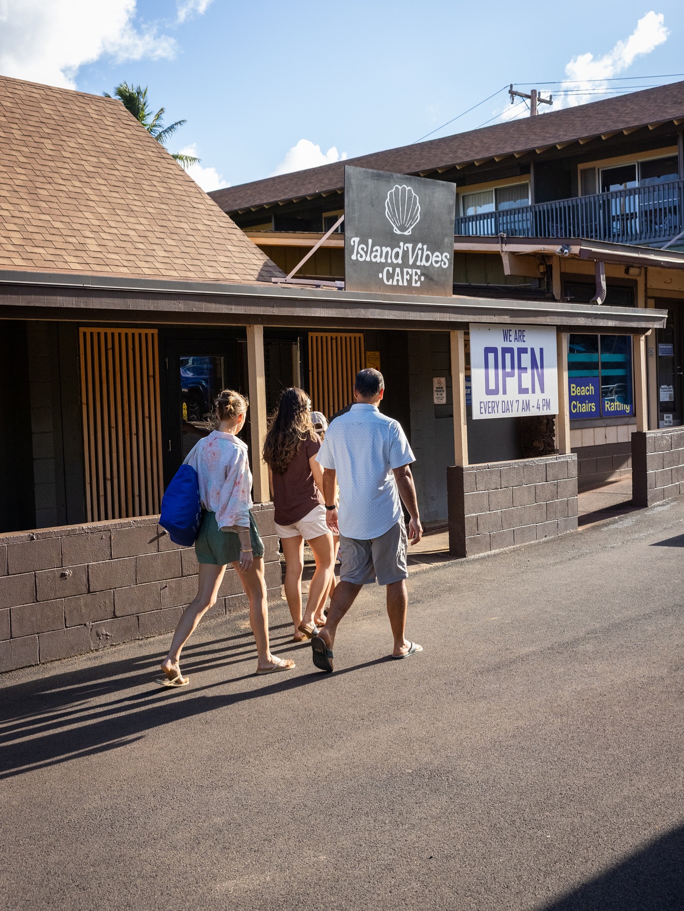 Digital Reach, People walking toward Island Vibes Cafe, open daily 7 AM-4 PM.