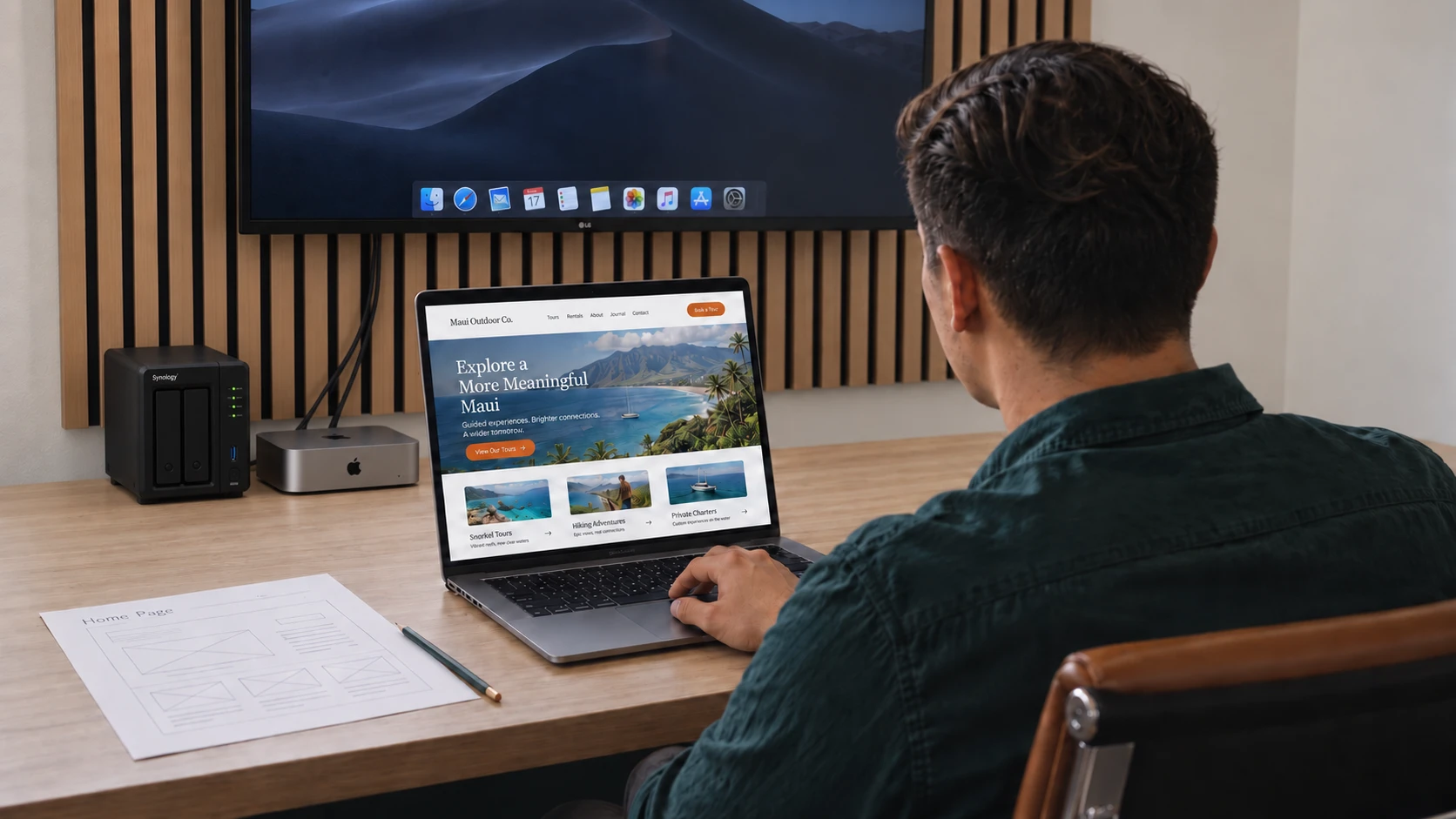 Shane Perry viewing a website design beside a printed page wireframe at his desk