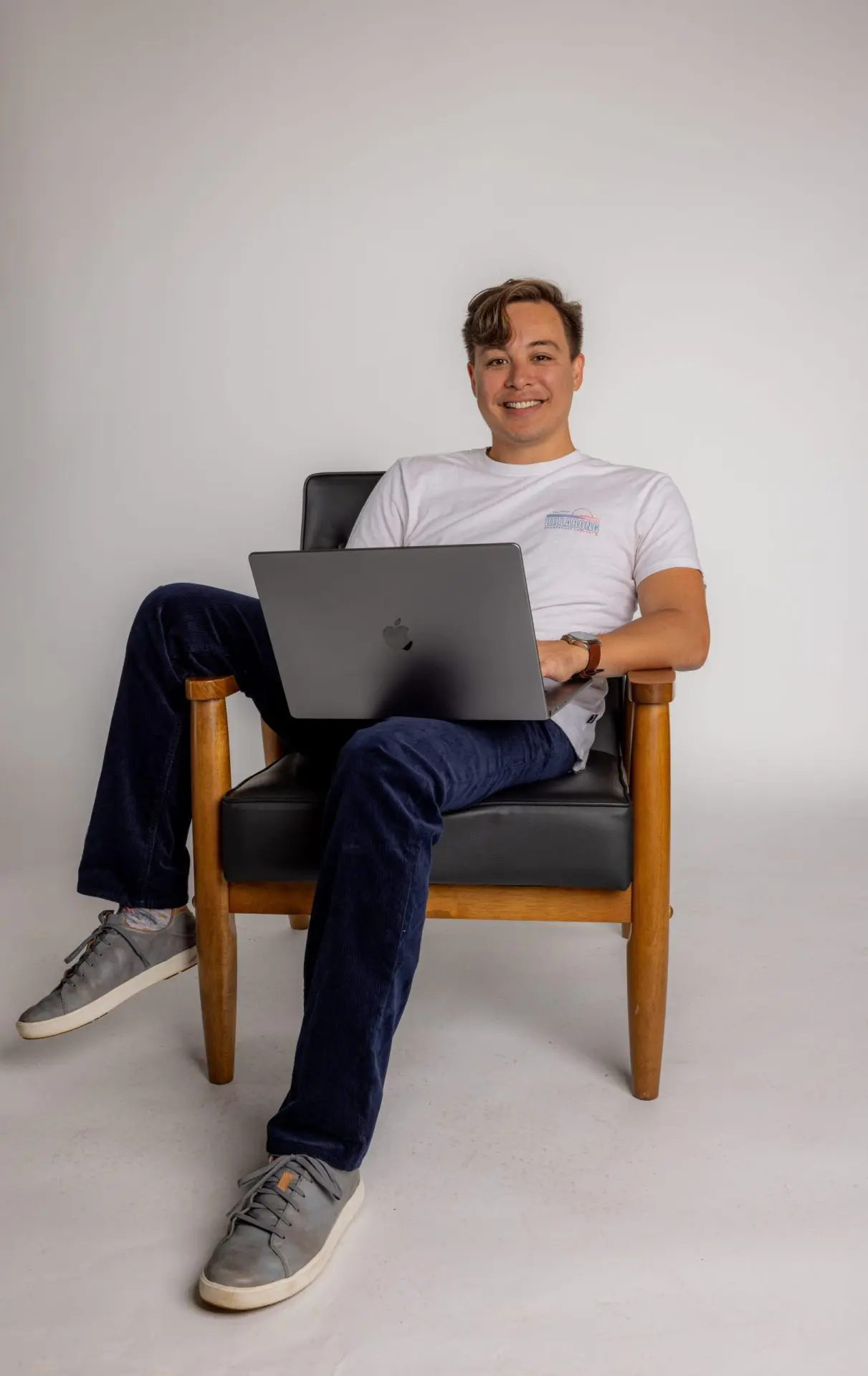 1F4A8006 copy Digital Reach, Smiling man working on laptop in armchair.