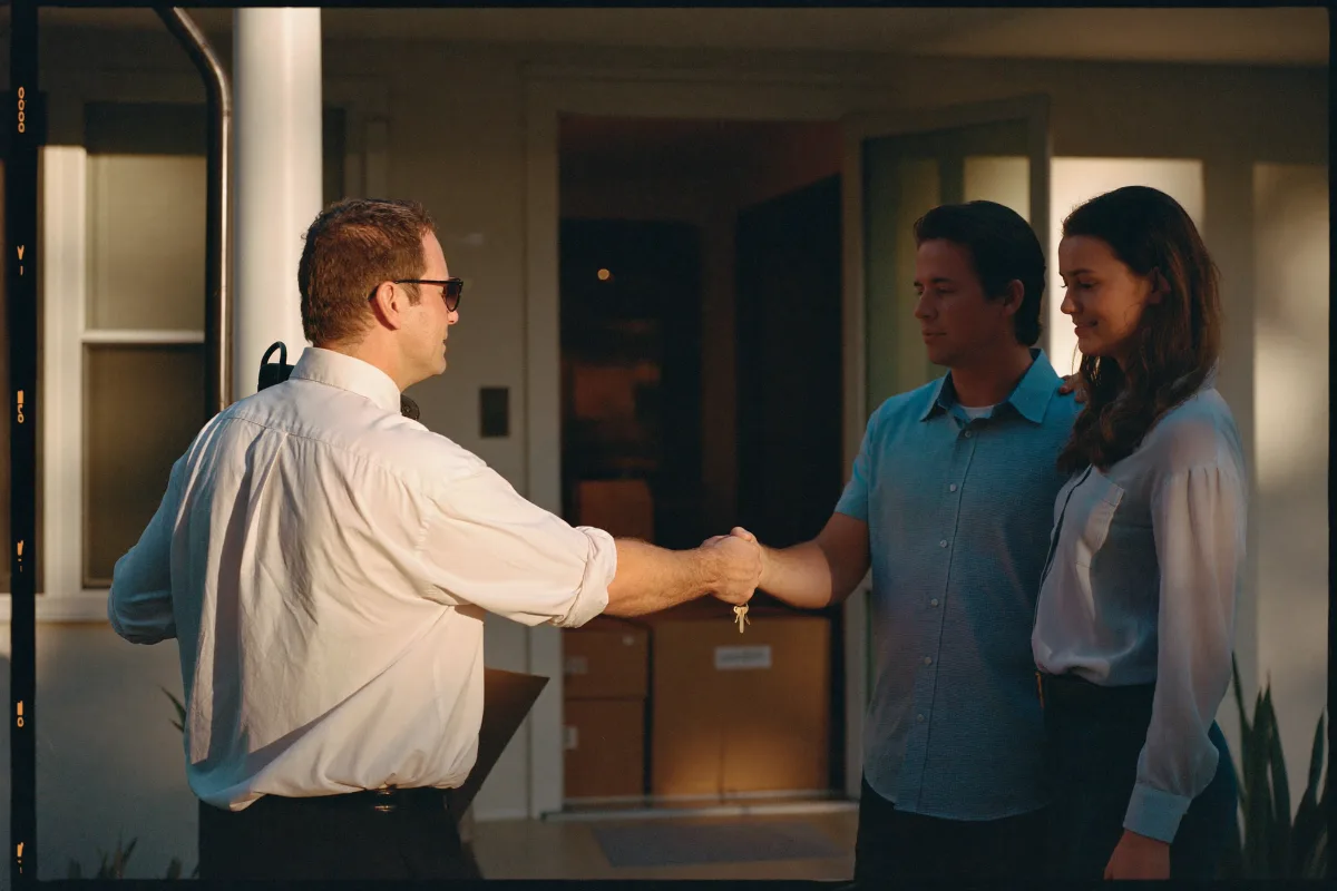 Real estate agent handing over the keys to a couple at the front door of their new home